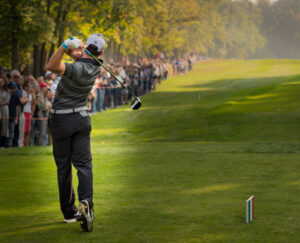 Golfer teeing off with a crowd in the background